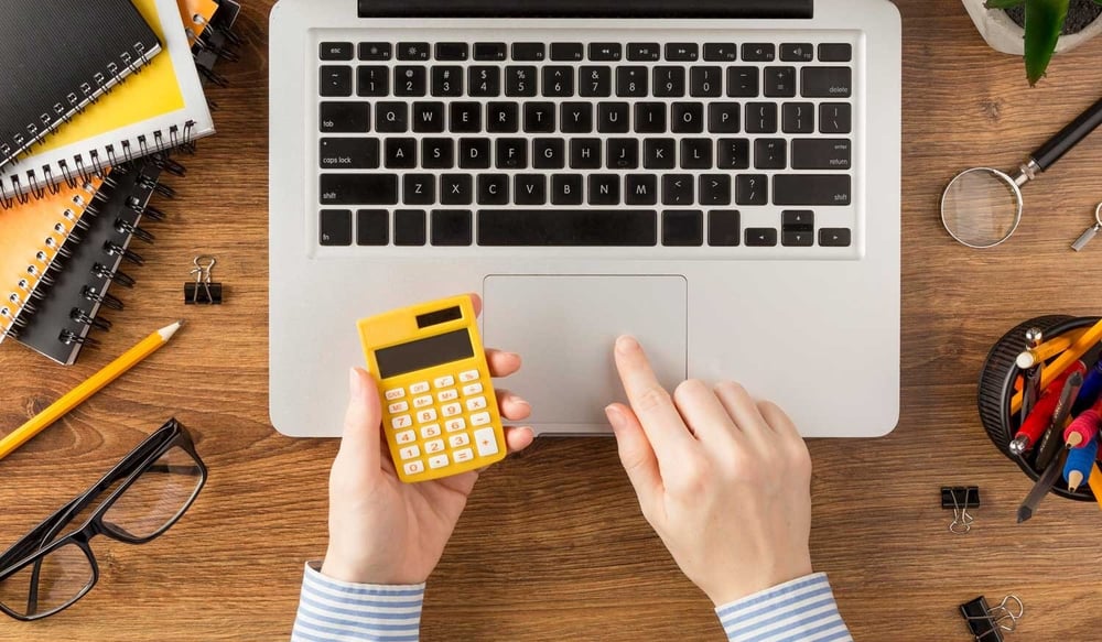 woman using computer and calculator to calculate IT support cost